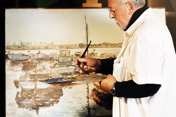 Old man artist painting oils in his studio.