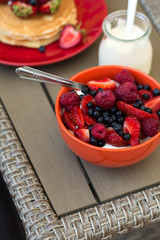 Healthy breakfast on garden furniture: cottage cheese with sour cream, strawberry, raspberry and blueberry, pancakes, yogurt and juice. Selective focus