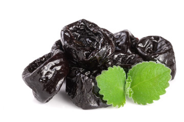 heap of dried plums or prunes with a mint leaf isolated on white background