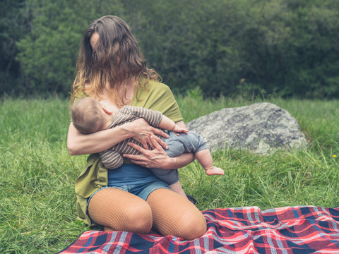 Young mother breastfeeding her baby in nature