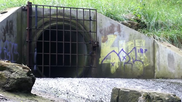 Creepy drainage pipe entrance with graffiti tags 