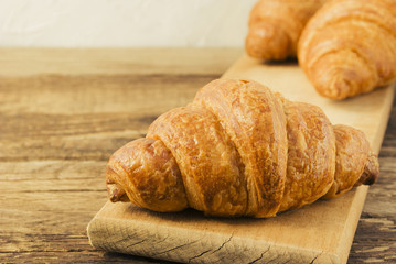 Tasty fresh croissants on old wooden background.