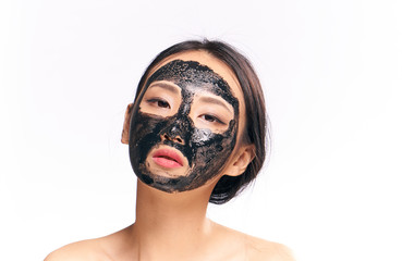 Beautiful young woman on white isolated background in black coal face mask, asian