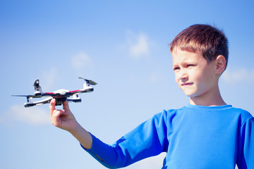 Boy playing with drone outdoors.