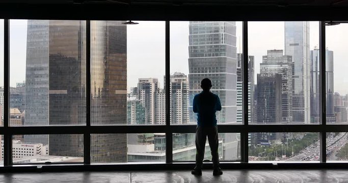 4k,a businessman Overlooking the urban business building from window,skyscrapers,economic center.