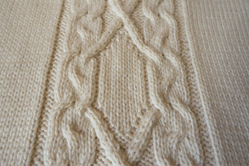 Fototapeta na wymiar Ivory handmade knitted fabric with plait pattern