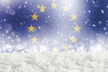 Defocused European union flag as a winter Christmas background with falling snow, snowdrift and bokeh