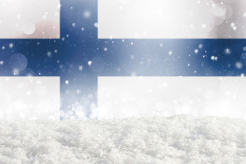 Defocused Finland flag as a winter Christmas background with falling snow, snowdrift and bokeh