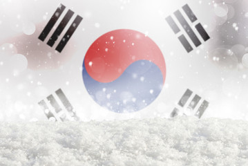 Defocused South Korea flag as a winter Christmas background with falling snow, snowdrift and bokeh