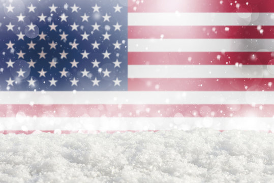Defocused American flag as a winter Christmas background with falling snow, snowdrift and bokeh