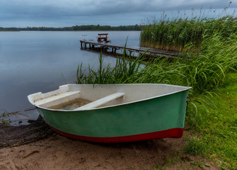 Fisherman boat on the beach during rain in the evening on Masuria, Poland