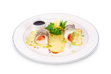 Rolls of dorado, zucchini and potatoes on a plate on a white background.