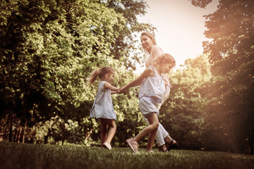 Mother playing on meadow with her two little daughter.