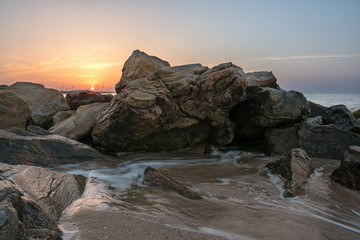 Fototapeta na wymiar Stones on the beach and windmills, dawn