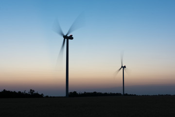 Wind turbines at sunset at dusk in a wheat field