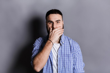 Surprised bearded man covering mouth with hand