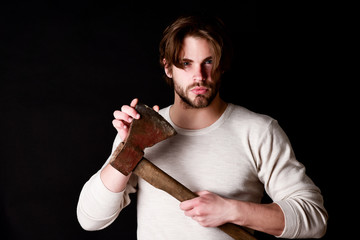 Assured young man checking sharpness of his old axe