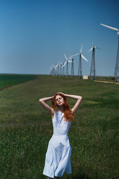 Beautiful young woman in a field near a windmill, summer, sun