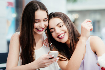 Girls have fun with a phone in coffee