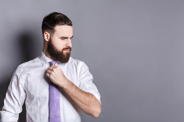 Handsome bearded businessman adjusting his tie