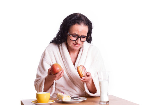 zweifelnde Frau im Bademantel beim Fr&uuml;hst&uuml;ck