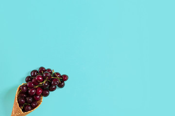 Cherries in waffle cone on blue background. Top view.