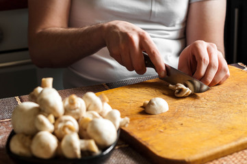 Obraz na płótnie Canvas man cutting mushrooms on wooden cutting board
