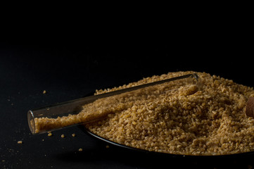 Dry bulgur wheat in brown wooden bowl isolated on dark wood