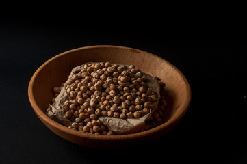 Grains of raw chickpeas in a wooden pot on on dark surface background