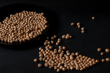 Grains of raw chickpeas in a wooden pot on on dark surface background