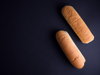 Two light brown hot dog buns isolated on black background