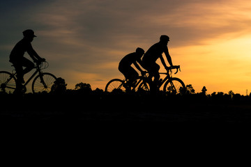 Silhouette of cyclist riding   bike on road at sunset.