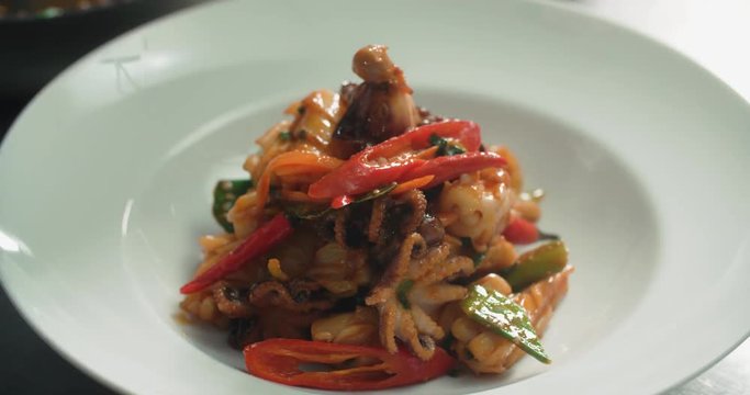 chef serves a dish of seafood on a plate adding the final ingredients