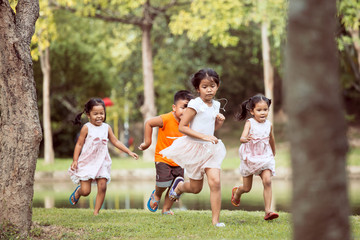 Fototapeta premium Asian children having fun to run and play together in the park in vintage color tone
