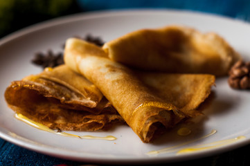 pancakes with honey syrup on a white plate. traditional crepe for pancake week or Shrovetide. crepes with roasted nuts