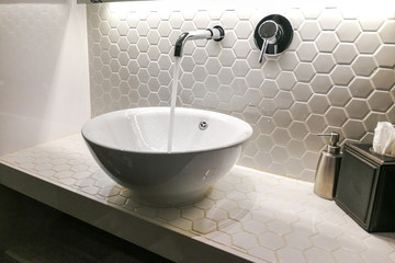 Modern wash basin with running water from tap faucet