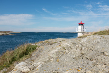 The beautiful little white lighthouse with its red ceilings, lit to control ships and boats, into the narrow passage from the sea into the beautiful Swedish archipelago, with the horizon and the blue 