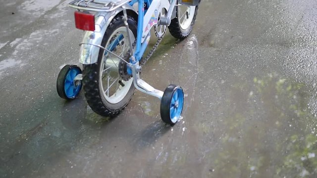A child riding a children's bike through the puddles