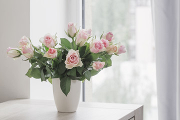 pink roses in vase on  background window