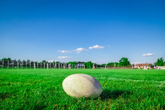 Rugby ball on field and players in the background