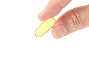 Close up male fingers holding the soft gel capsule on white background, optimal oil supplement in take concept.