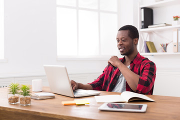 Fototapeta premium Smiling black businessman in casual office, work with laptop