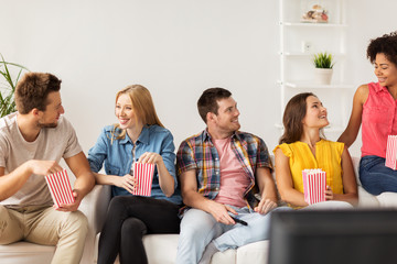 happy friends with popcorn and tv remote at home