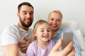 Fototapeta premium happy family taking selfie by smartphone at home