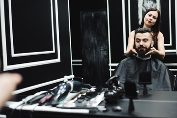 Master cuts hair and beard of men in the barbershop, hairdresser makes hairstyle for a young man