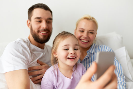 happy family taking selfie by smartphone at home
