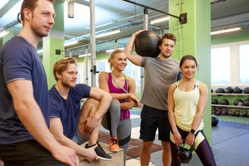 group of friends with sports equipment in gym