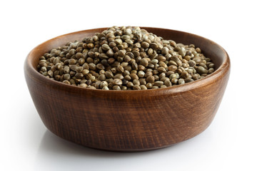 Hemp seeds in dark wooden bowl isolated on white.