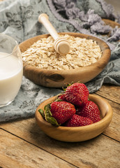 Healthy breakfast concept with oat flakes and fresh berries on rustic background. Food made of granola and musli. Healthy banana smoothie with blackberries, honey and milk.