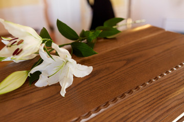 lily flower on wooden coffin at funeral in church